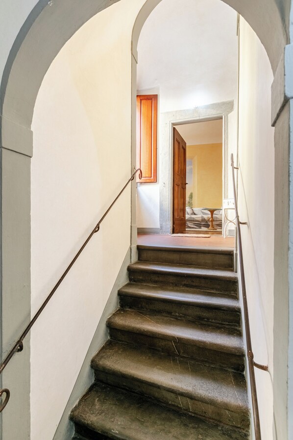 A staircase with a handrail, leading to a room with a bed and a window.