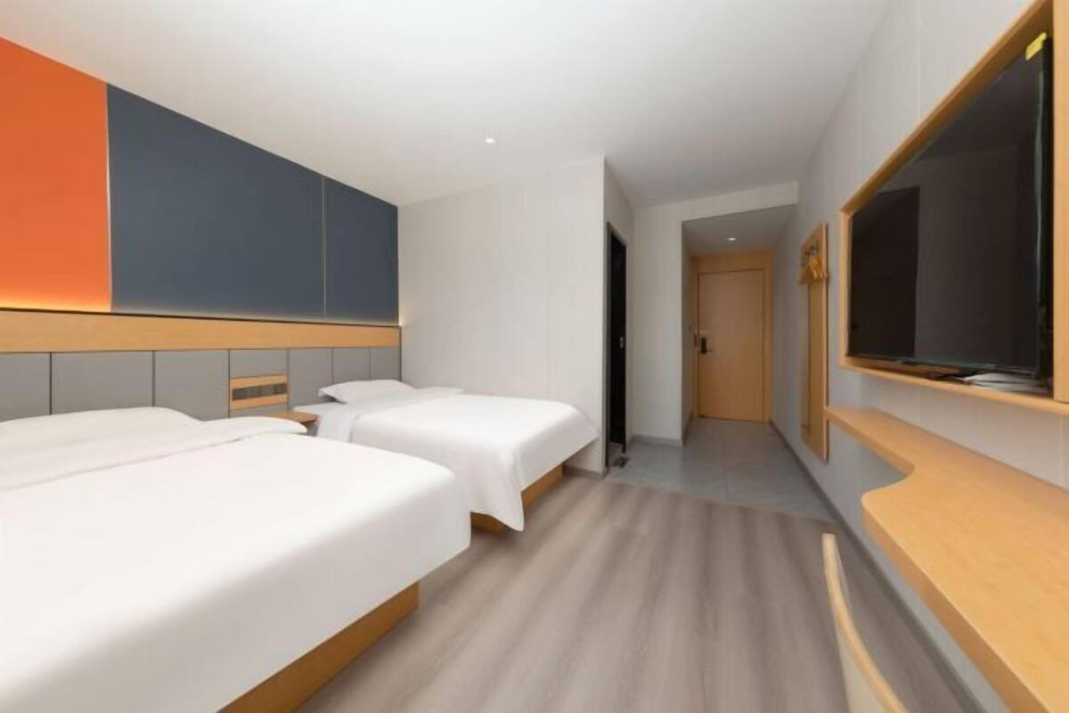 Habitación de hotel con dos camas, un televisor, un cabecero de madera y un ventanal grande.