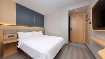 Una habitación de hotel moderna con cama, mesitas de noche, un armario y televisión.