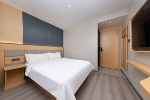 A modern hotel room with a bed, bedside tables, a wardrobe, and a television.