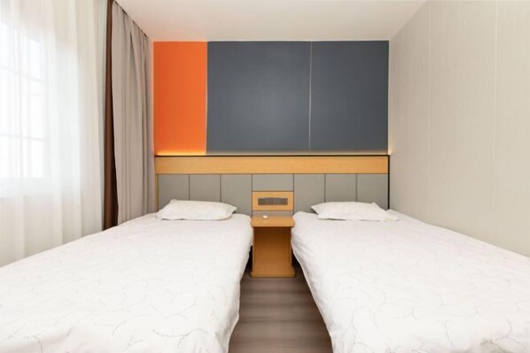 A hotel room with two beds, a nightstand, and a wall unit. - Shanghai Comet Hotel (Shanghai)
