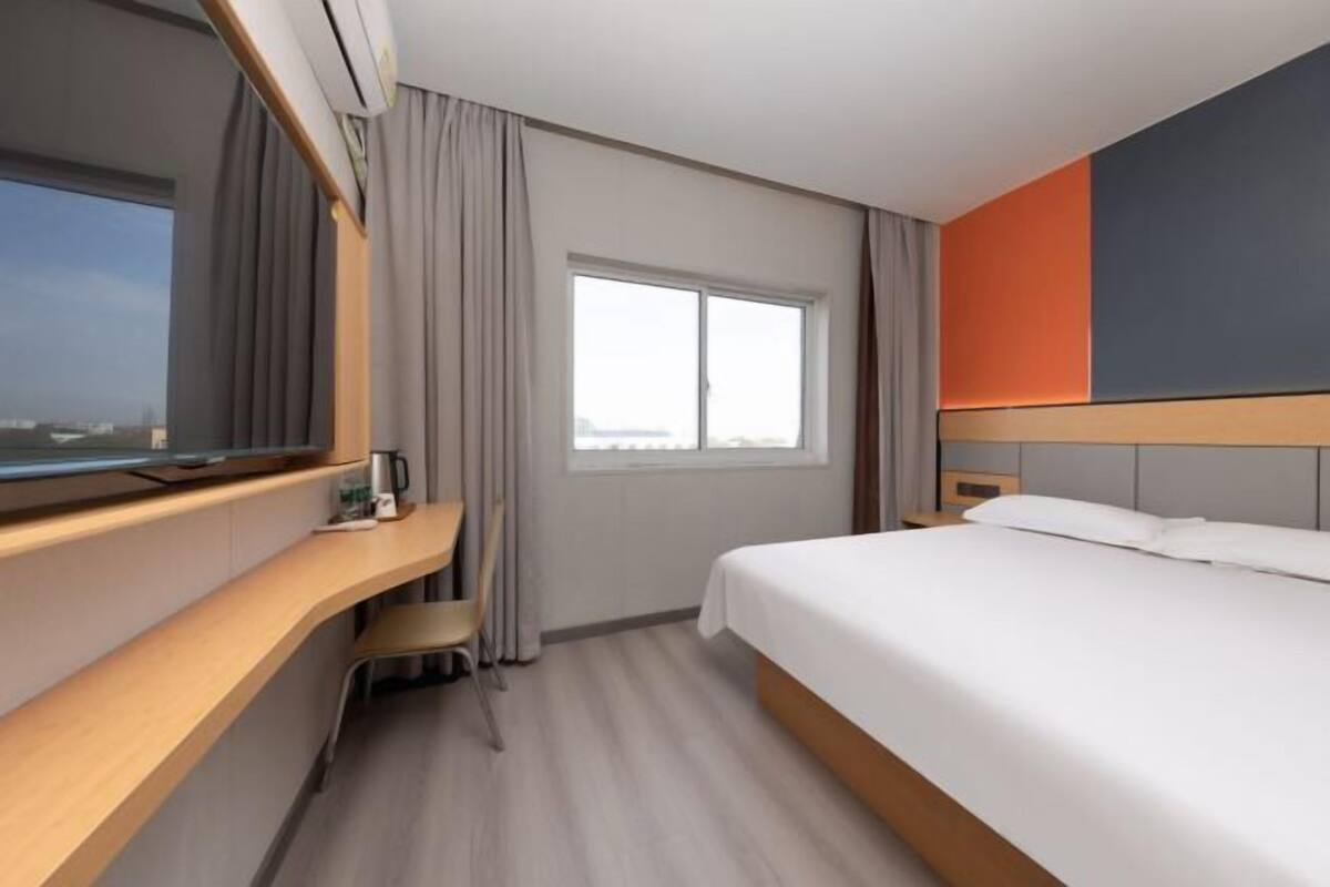 Habitación de hotel con cama, escritorio, silla, ventana y televisor.
