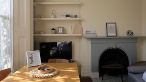 Una sala de estar con chimenea, televisor y una mesa con una cesta y un cartel.