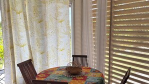 Comedor con una mesa redonda cubierta con mantel floral, rodeado de sillas de madera.