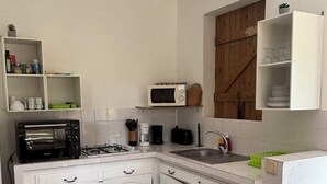 Una cocina compacta con armarios blancos, un microondas, un tostador y un lavamanos.