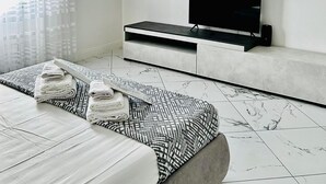 A modern bedroom with a bed, a TV, and a wall-mounted shelf.