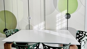 A modern dining area with a white table and chairs, geometric wall art, and a power outlet.