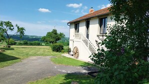 A house with a paved driveway, a wooden wheel, and a stone wall.