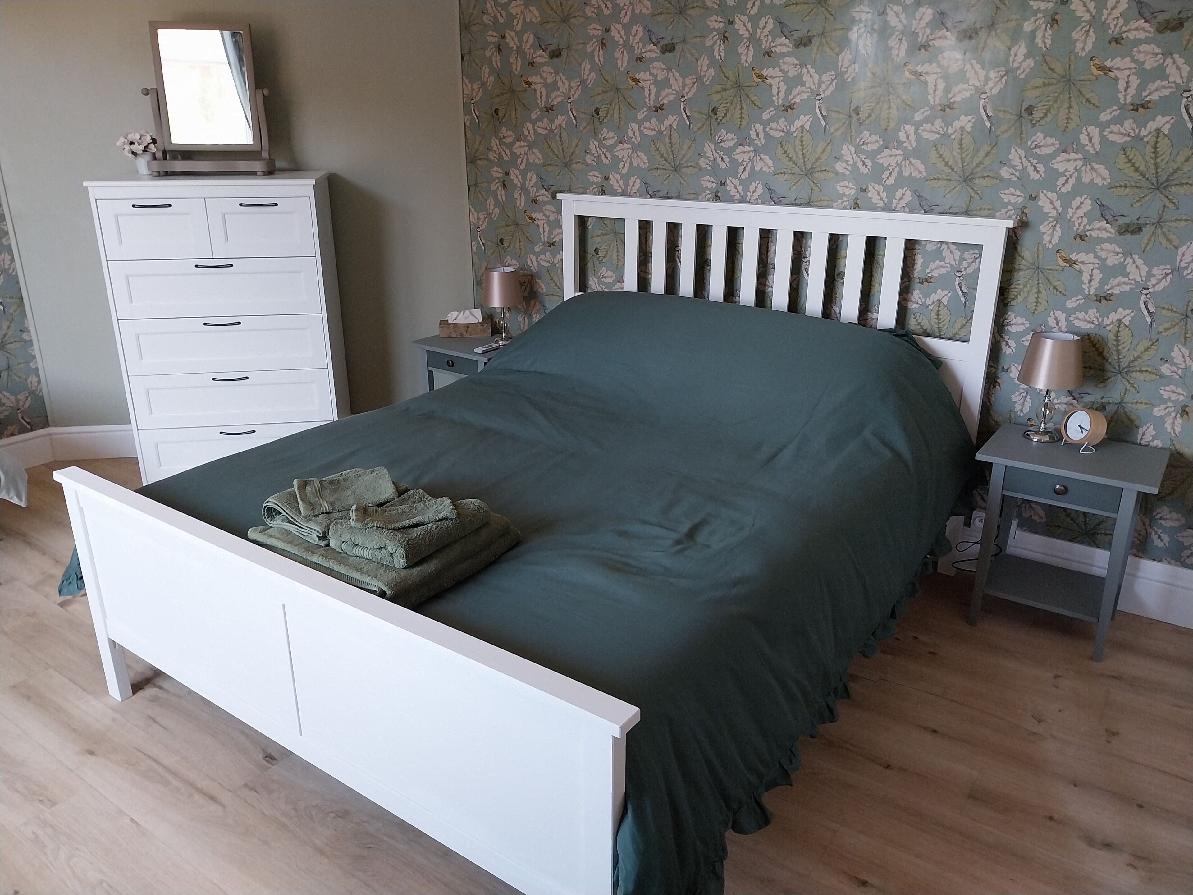 Un dormitorio con una cama, un tocador, una mesita de noche y un espejo.