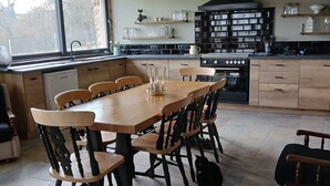 A spacious kitchen with a large island, wooden chairs, and a dining table.