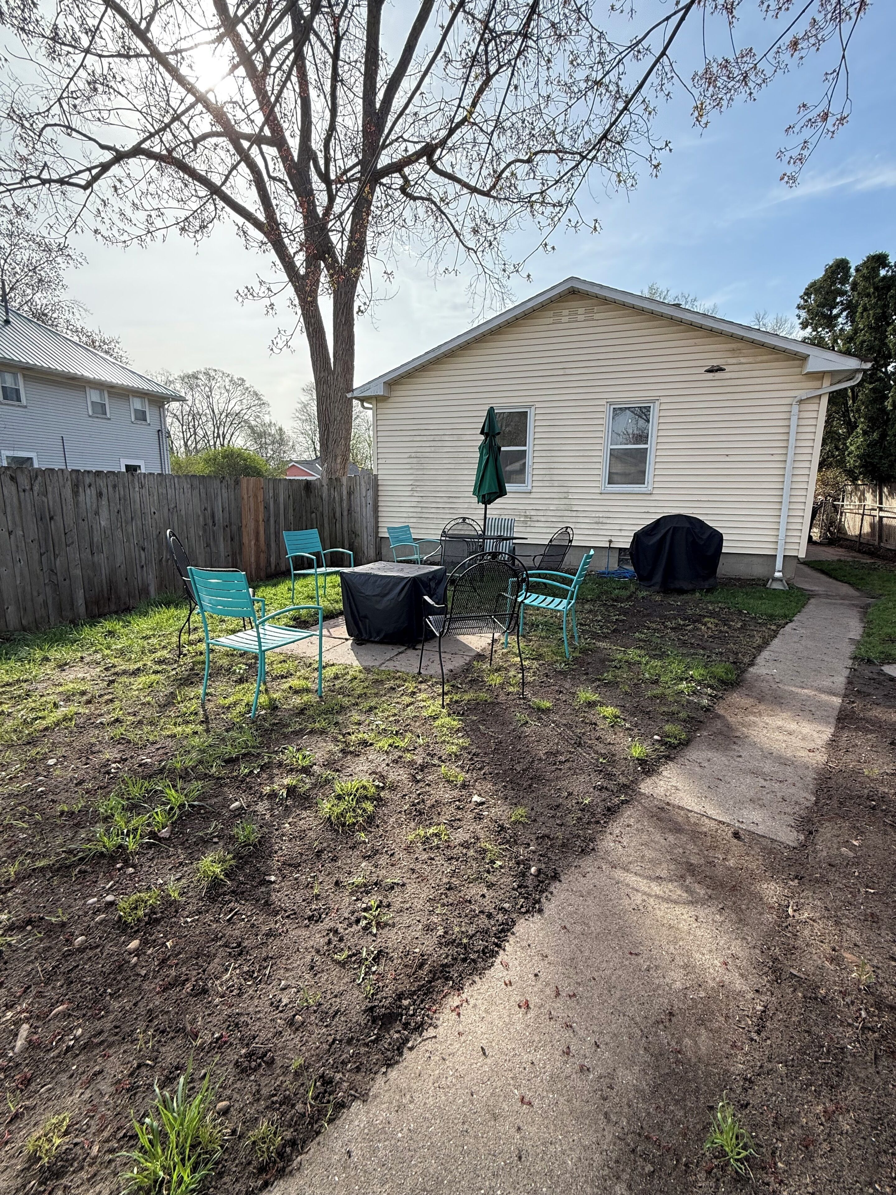 Un jardin avec un espace patio, une table couverte et des chaises.