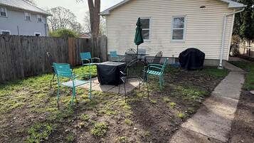 Un jardin avec un espace patio, une table couverte et des chaises.