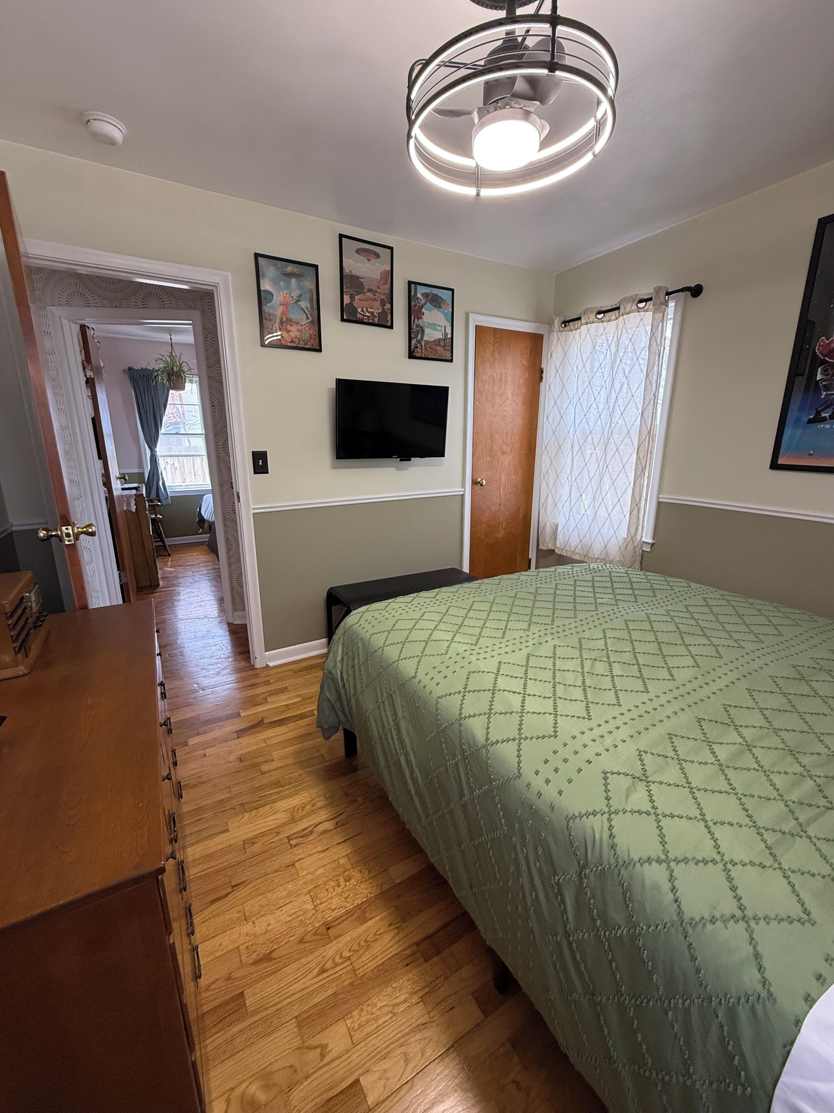 Une chambre à coucher avec un lit, une télévision, une porte et un couloir menant à une autre pièce.