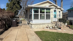 A single-story house with a covered porch, large windows, and a front yard with a small garden.