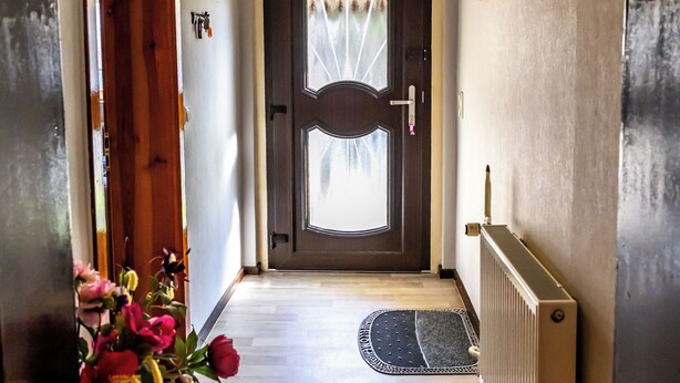 A hallway with a wooden door, a radiator, and a vase with flowers. - Cozy and quiet vacation apartment with private garden in beautiful Thuringia (Schmalkalden)