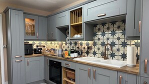 Een moderne keuken met grijze kastjes, een houten aanrechtblad en een spatwand met stermotieven.