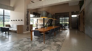 Un espace de travail partagé moderne, doté d’une grande table en bois, de plusieurs chaises et d’un éclairage suspendu.