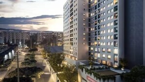 Un immeuble moderne à plusieurs étages, doté d’une cour intérieure verdoyante et d’une enseigne bien visible.
