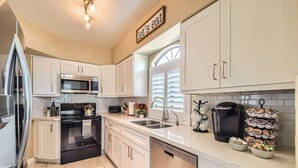 A modern kitchen with white cabinets, a stainless steel refrigerator, a microwave, a stove, and a coffee maker. - Scottsdale 3BR Kierland Condo—Pool, Hot Tub, TPC (Scottsdale)