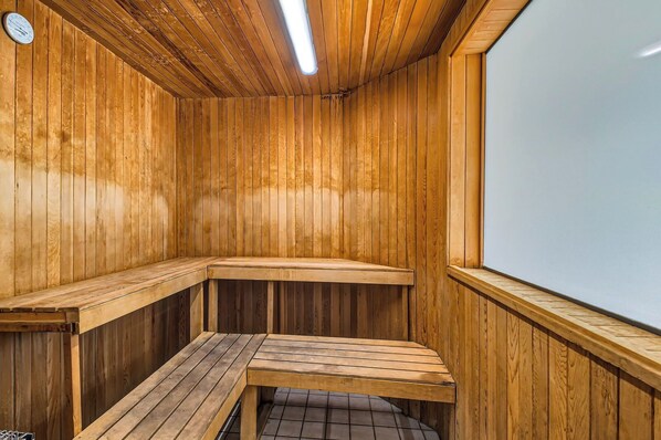 A wooden sauna with benches and a sloped ceiling.