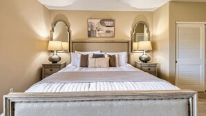 A bedroom with a large bed, two bedside tables with lamps, a ceiling fan, and a door with louvered shutters. - Scottsdale 3BR Kierland Condo—Pool, Hot Tub, TPC (Scottsdale)