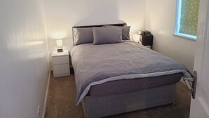 A small, neatly arranged bedroom with a single bed, a bedside table, a lamp, and a window with a polka dot blind. - Rusper Retreat - Spacious Home Near Gatwick (Crawley)