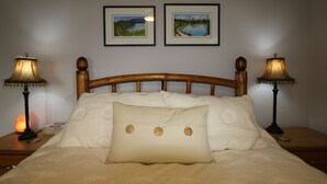 A neatly made bed with a large pillow and two lamps on either side. - Private Suite with Amazing Lake View (Naramata)