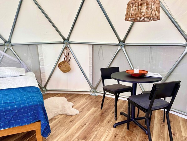 A cozy interior with a bed, a round table with chairs, and a hanging basket.