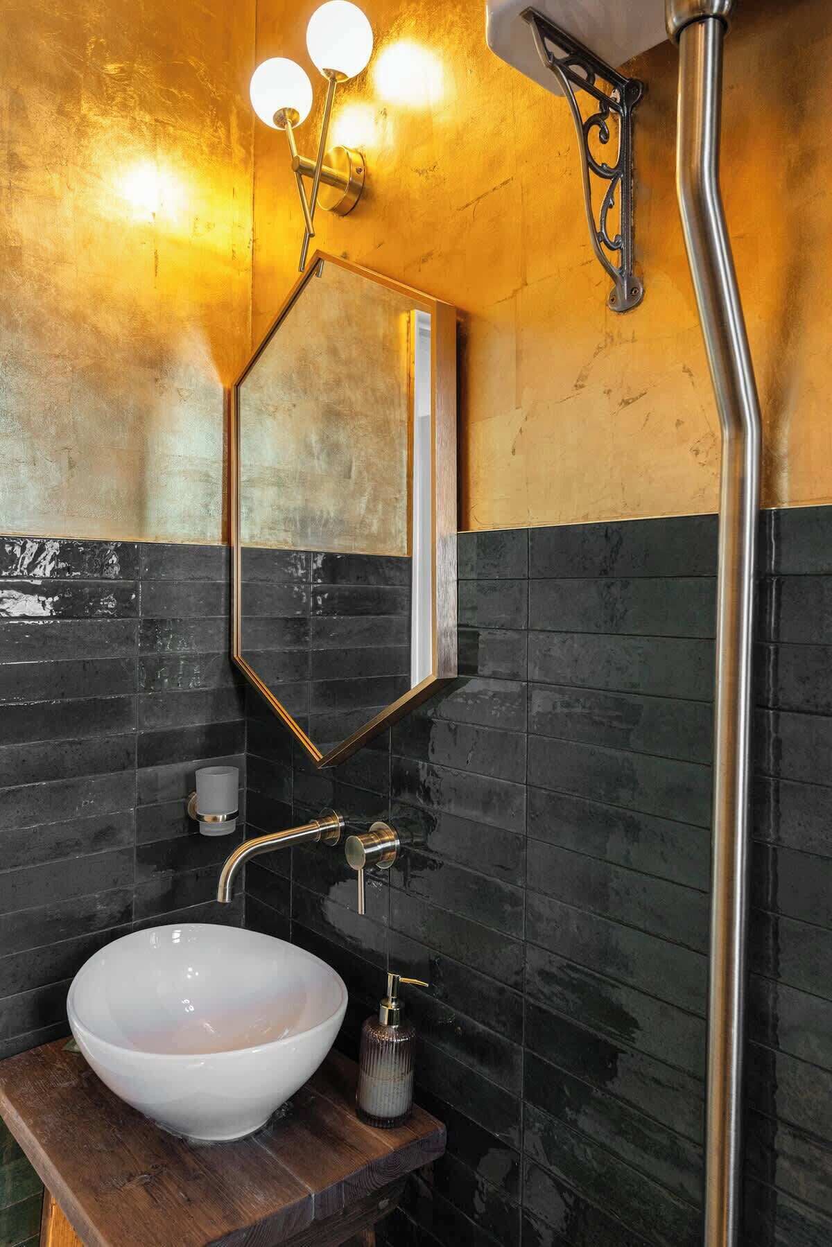A bathroom with a white vessel sink, a mirror, and a wall-mounted light fixture.