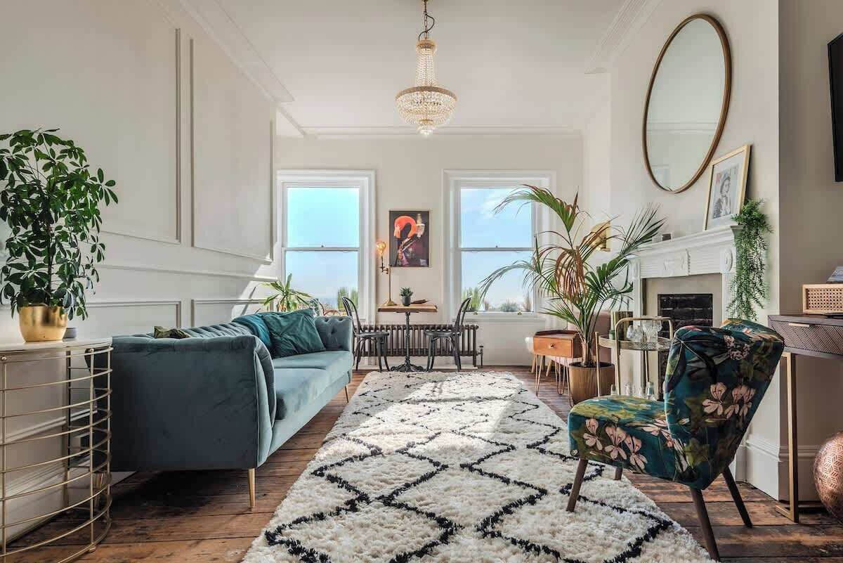 Een woonkamer met een bank, fauteuil en een vloerkleed met patroon.
