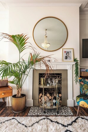 A living room with a fireplace, a round mirror, a chandelier, and a potted plant. - The Wellington - style, charm, stunning sea views (Ramsgate)