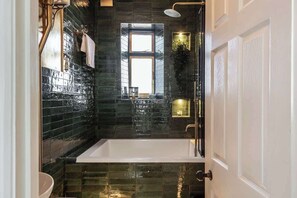 Ein modernes Badezimmer mit einer groĂen Badewanne, einem Fenster und einem Spiegel.