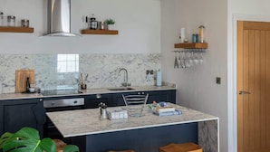 Une cuisine moderne dotée d’une verrière, de plans de travail en marbre et d’un îlot central avec des tabourets de bar.