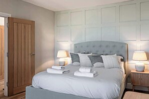 Una camera da letto con un letto grande, lampade ai comodini, un armadio in legno e una testiera chiara.