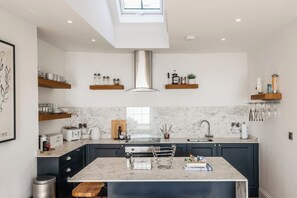 A modern kitchen with marble countertops, a central island, and built-in appliances.