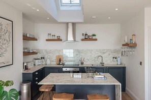 Una cucina moderna con isola centrale, mobili scuri e piani in marmo.
