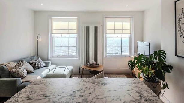 Un salon moderne avec une grande table en marbre, un canapé et une plante en pot.