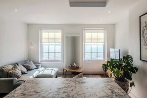 Een moderne woonkamer met een grote marmeren tafel, een bank en een potplant.