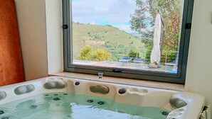 A hot tub with a view of a hillside and outdoor furniture. - Ville Petrara: villa con piscina e spa nei vigneti (Poppano San mango sul calore)