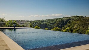 A rectangular infinity pool with a clear view of a hilly landscape in the background. - Ville Petrara: villa con piscina e spa nei vigneti (Poppano San mango sul calore)