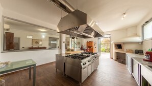 A modern kitchen with a central island, stainless steel appliances, and a large range hood. - Ville Petrara: villa con piscina e spa nei vigneti (Poppano San mango sul calore)