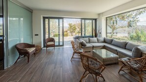 A spacious living area with a large sectional sofa, wicker chairs, and a glass coffee table. - Ville Petrara: villa con piscina e spa nei vigneti (Poppano San mango sul calore)