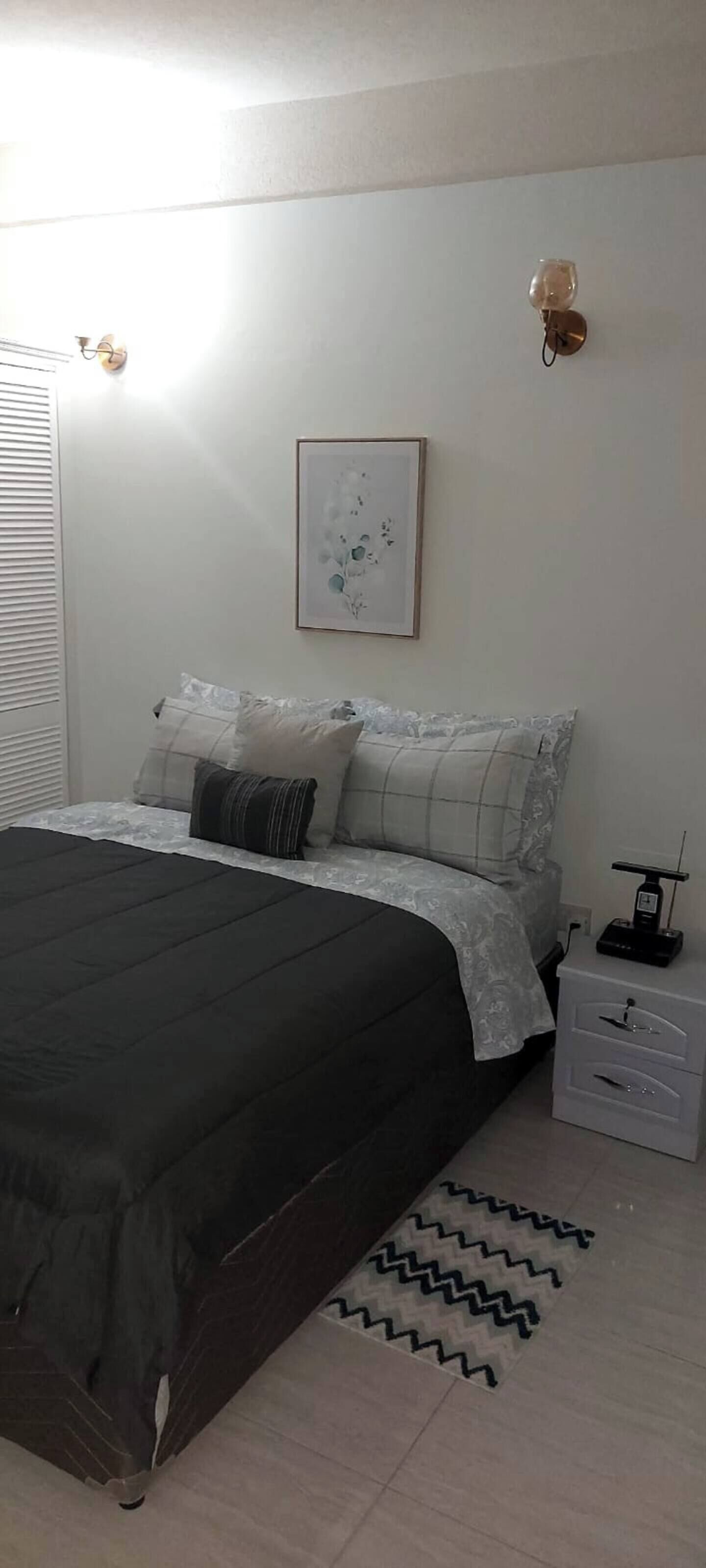 Ein Schlafzimmer mit Bett, Nachttisch, Lampe und einem gerahmten Bild an der Wand.
