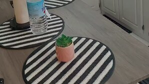 A kitchen with white cabinets, a microwave, a toaster, a blender, and a water bottle on a table with striped placemats. - Newly constructed luxury apartment. -Pristine Stay- (Roseau)
