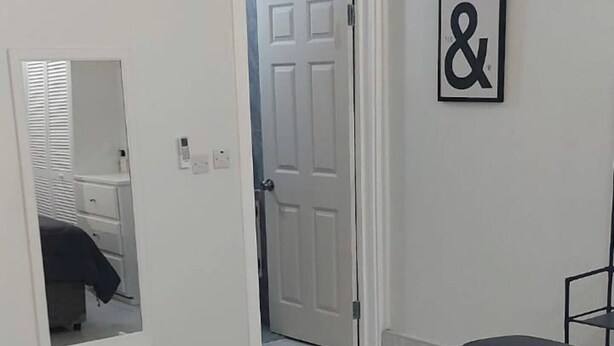A bedroom with a bed, a dresser, a mirror, and a door. - Newly constructed luxury apartment. -Pristine Stay- (Roseau)