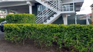 A modern building with a white exterior, a staircase, and a well-maintained hedge. - Newly constructed luxury apartment. -Pristine Stay- (Roseau)
