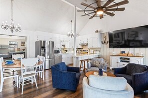 Enjoy a spacious living area with a kitchen, dining, and lounge space, featuring a central island, flat-screen TV, and comfortable seating.