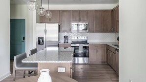 A modern kitchen with granite countertops, stainless steel appliances, and wooden cabinets.