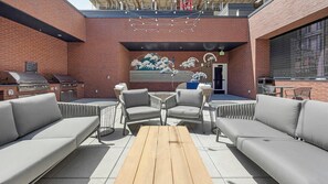 Un patio al aire libre con pared de ladrillo, una parrilla y zona de estar.
