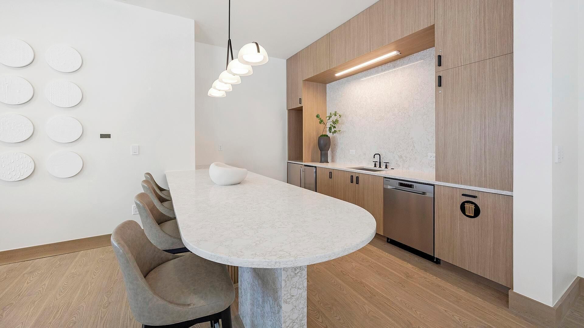Une cuisine moderne dotée d’un plan de travail en marbre, de meubles en bois et d’un lave-vaisselle encastré.